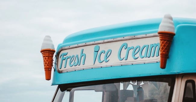 The front of a blue ice cream van with the words Fresh Ice Cream