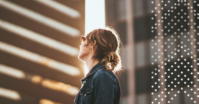 A young woman looks up a high rises in the city