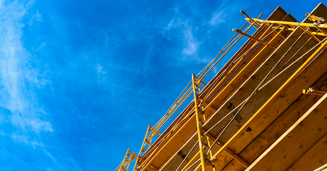 yellow scaffolding on a buildign against a blue sky