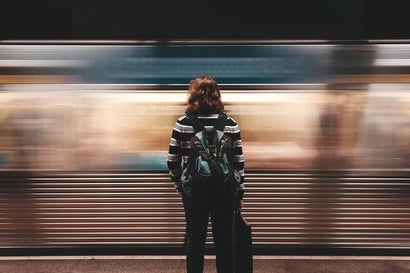 a young person stands at a subway train with their back to us
