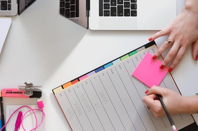 a person at a desk planning with a calendar laptop and highlighter pens