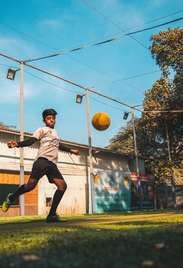 A boy kicks a soccer ball with a look of intense concentration on his face