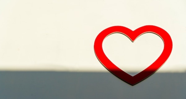 A red heart on a white wall in sunlight and shadow