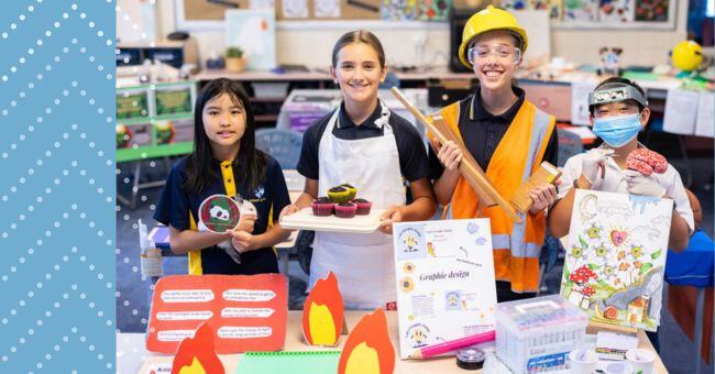 An image of four students dressed as: an animal trainer, a chef, an architect, a brain surgeon. In front of them on the table are projectrs investigating careers in fire fighting and graphic design among others.