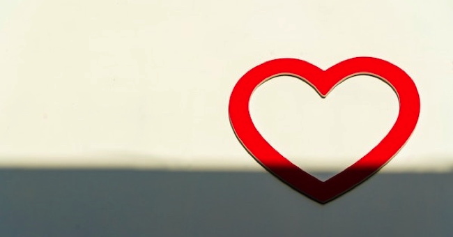A red heart on a white wall in sunlight and shadow